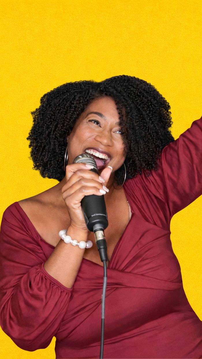 Rene singing into a microphone against a yellow background